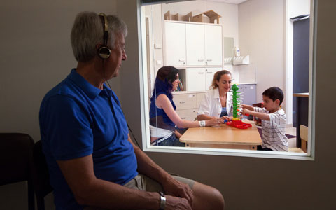 הורה צופה בטיפול קלינאות תקשורת של בנו 