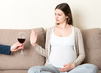 אישה בהריון מסרבת לכוס יין
